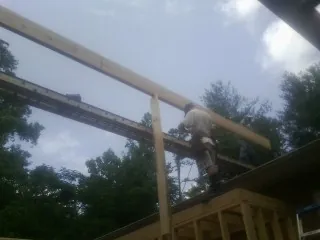 Carpenter setting a ridge beam over a new addition frame — Ice Dam Removal by Roofing Brothers in Coinjock