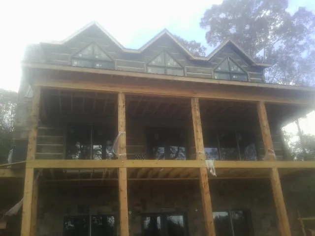 Dormers and porch framing on a large log home under construction — Roof Coating work by our crew in Coinjock
