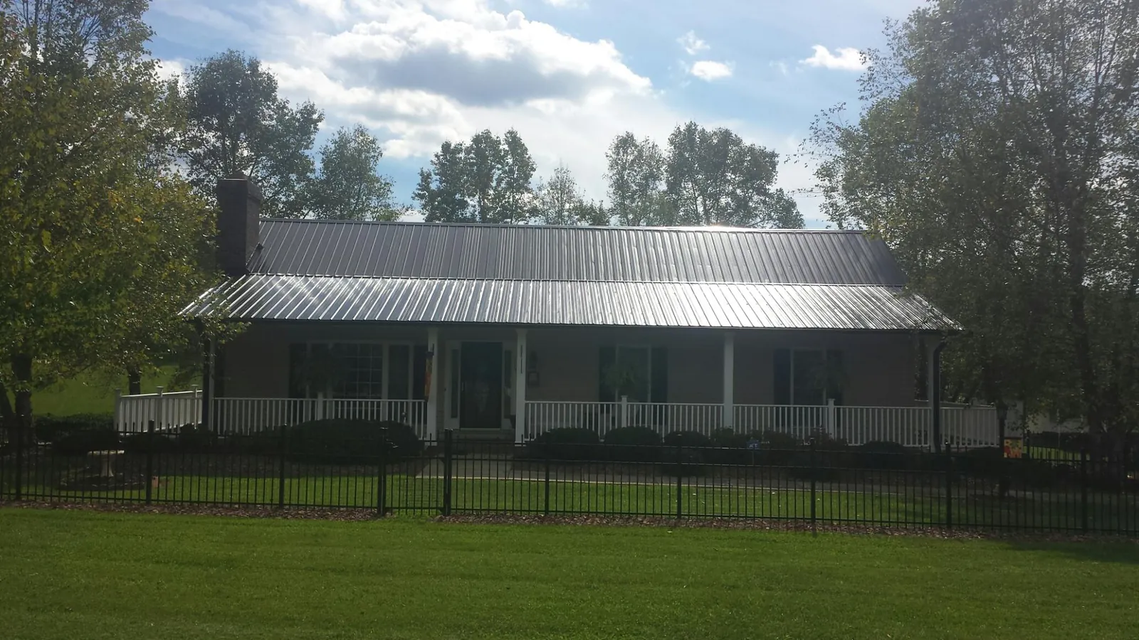 Gray metal roof on a brick ranch with a full width front porch — Gutter Guard Installation work by our crew in Coinjock