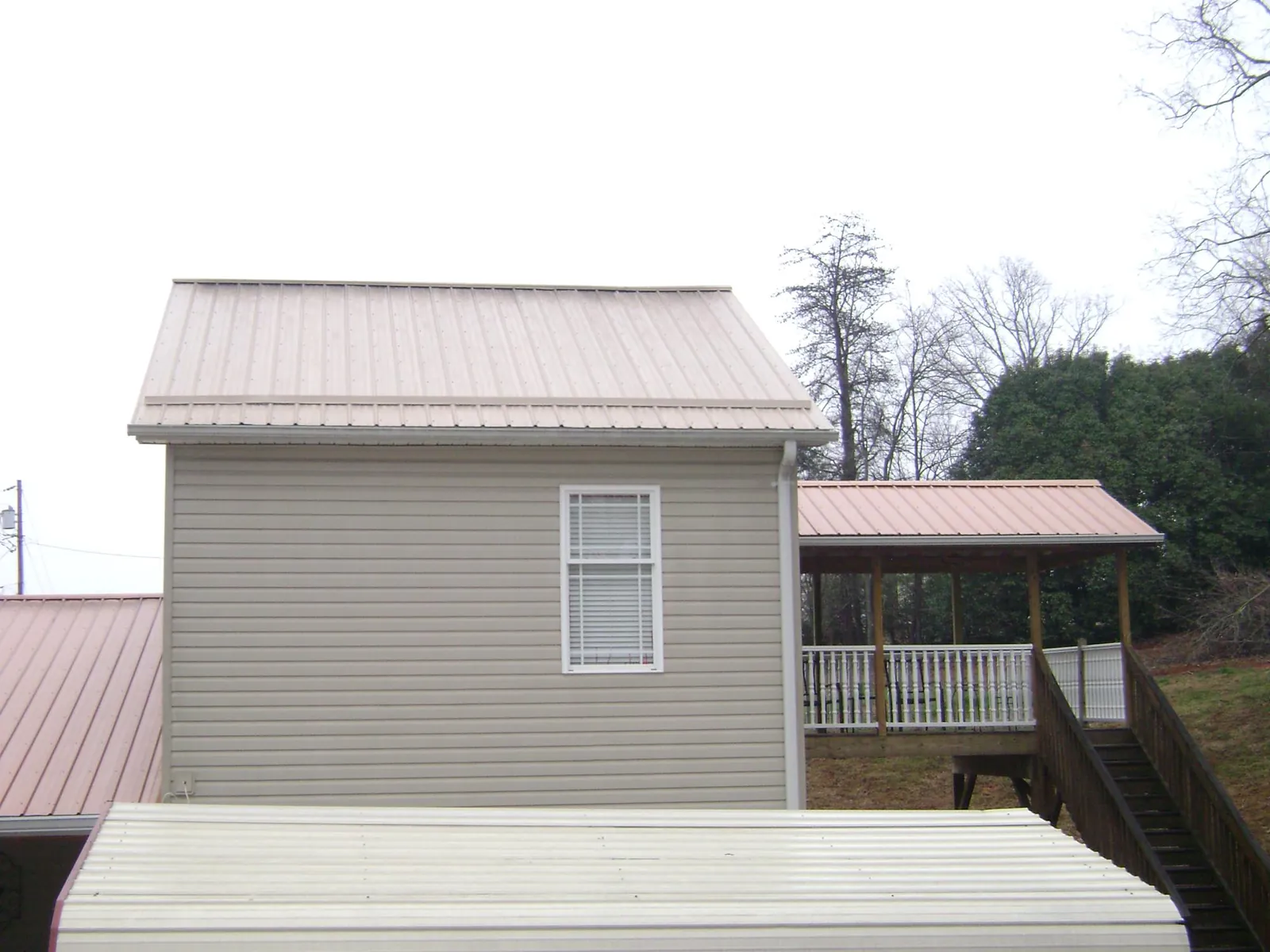 Tan metal roofs on a two story addition and attached porch, from a Roof Replacement job in Coinjock