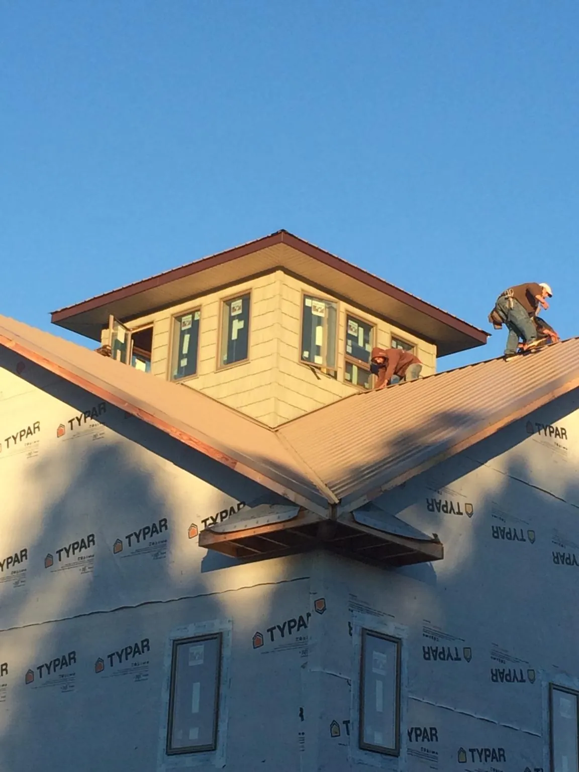 Roofers working around a rooftop cupola on a new metal roof at sunset — Roof Waterproofing in Coinjock by Roofing Brothers